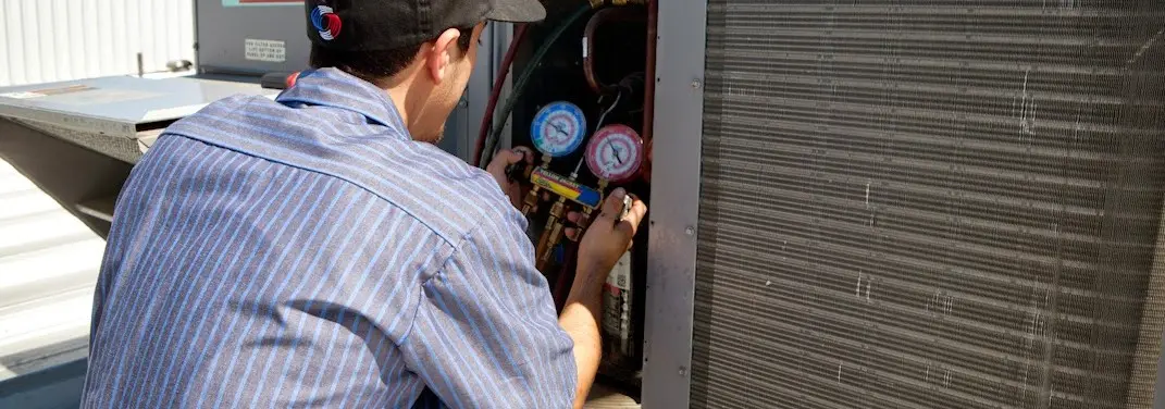 HVAC technician servicing a condenser unit in Dennis