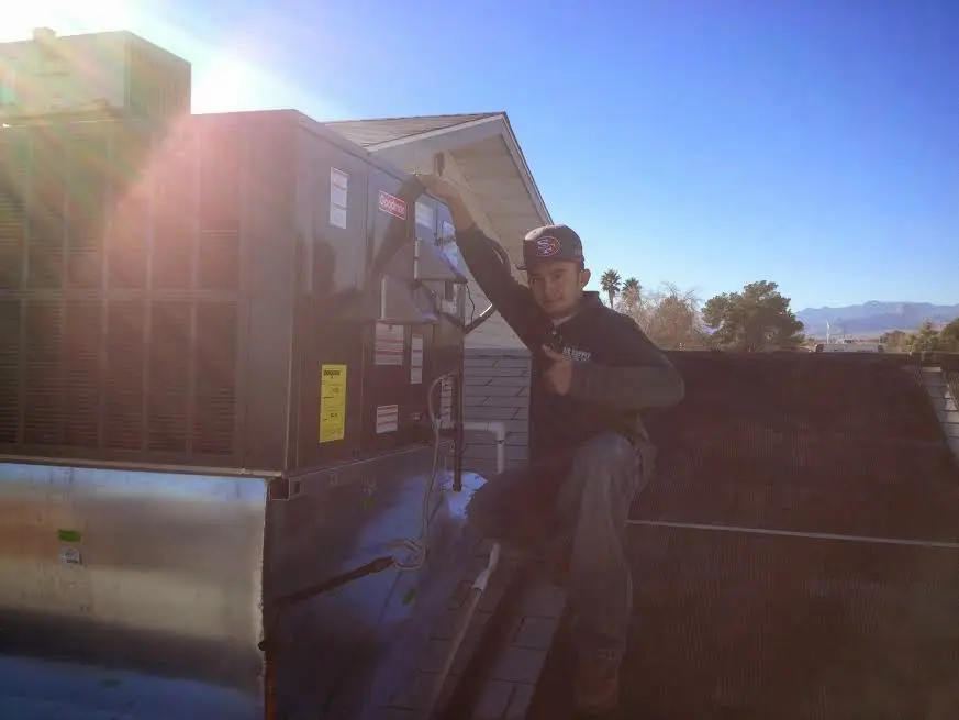 HVAC technician performing AC Tune-Up on a rooftop unit in Dennis